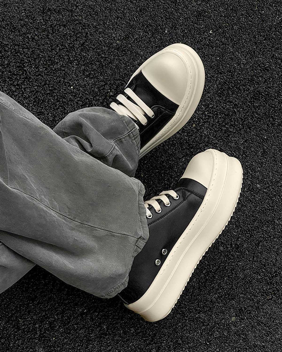 Chunky Low-Top Streetwear Sneakers featuring black uppers and cream chunky soles, worn with gray pants, embodying bold, modern streetwear style with German-trainer inspiration.