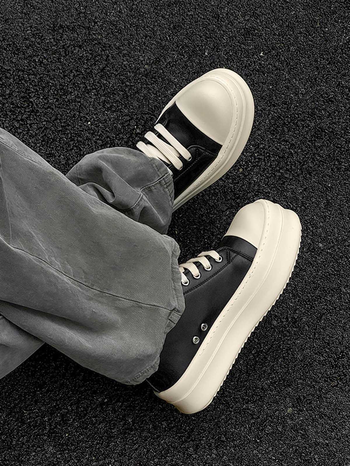 Chunky Low-Top Streetwear Sneakers featuring black uppers and cream chunky soles, worn with gray pants, embodying bold, modern streetwear style with German-trainer inspiration.