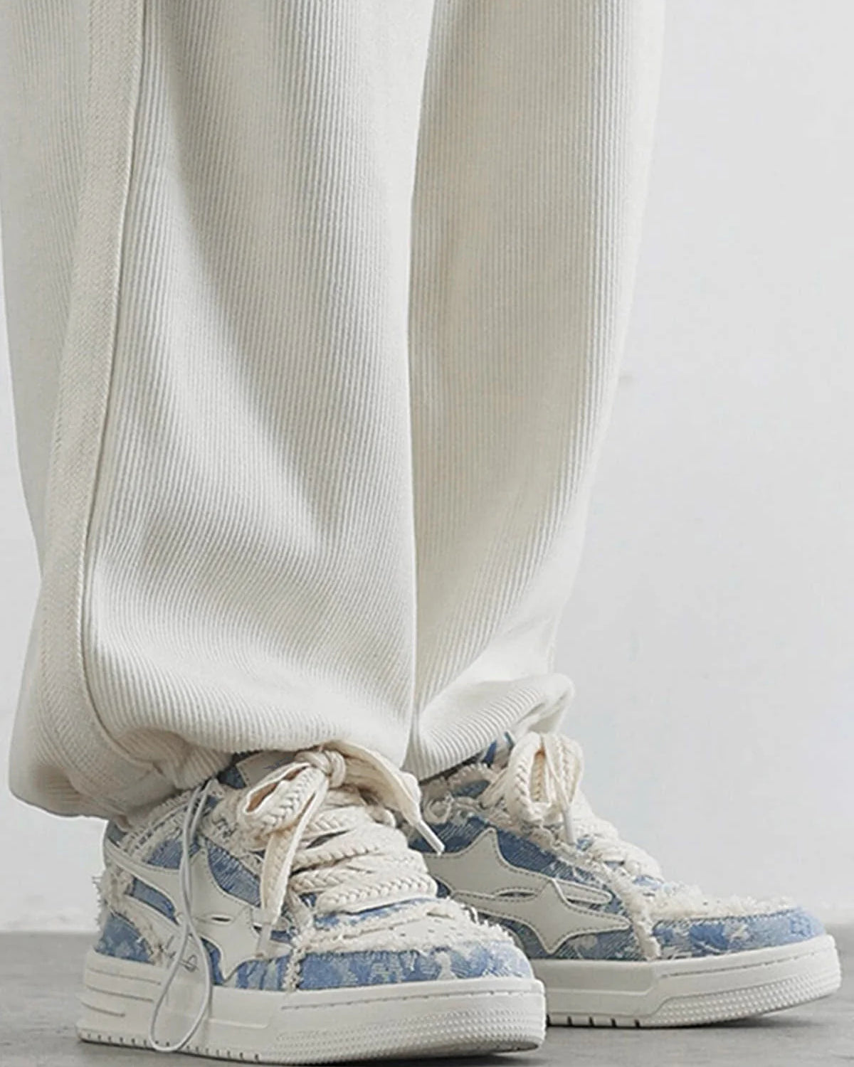 Distressed Denim Low-Top Street Sneakers with chunky off-white soles, frayed patchwork uppers, and rope-style laces, highlighting a bold streetwear aesthetic.