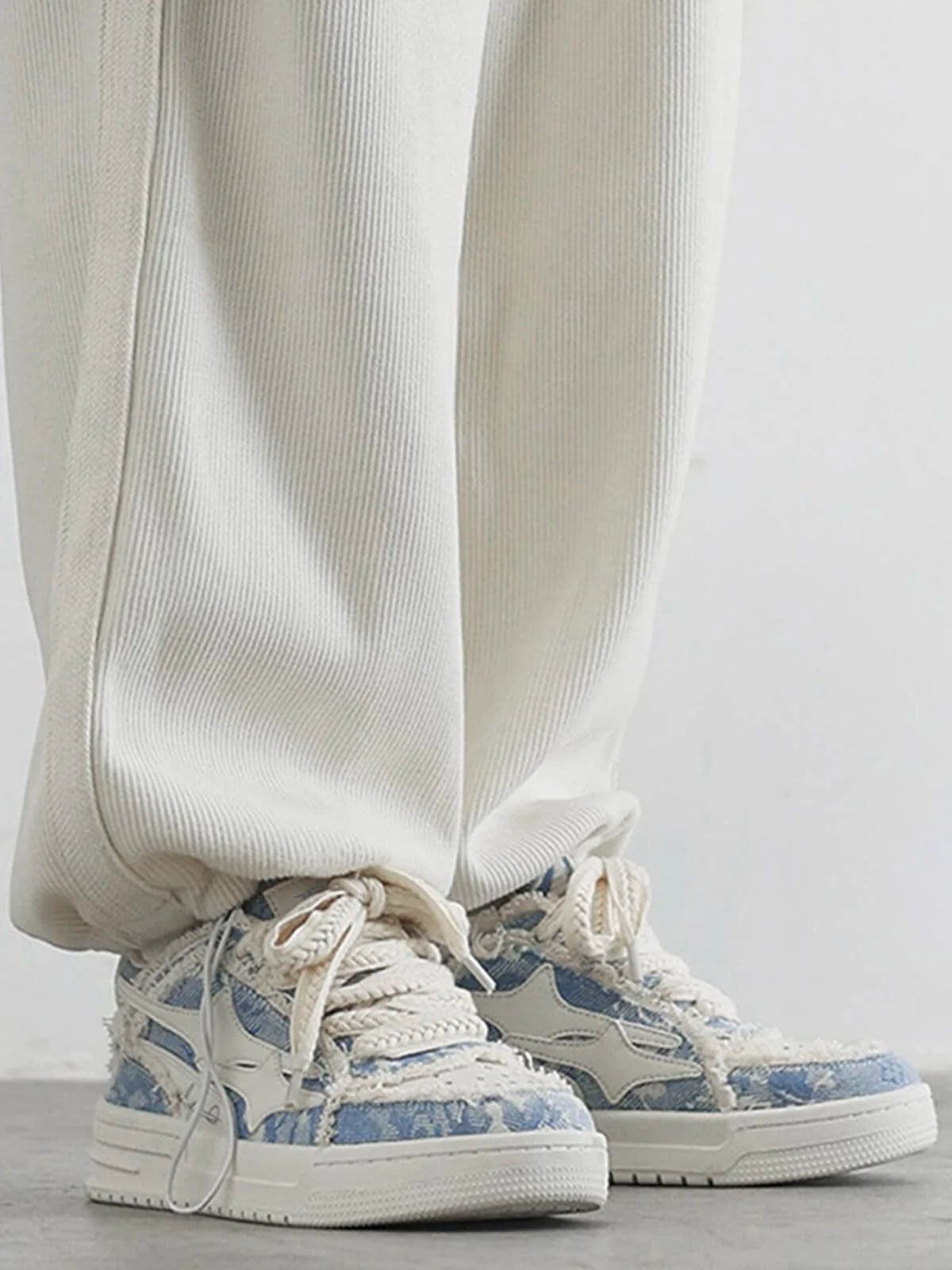 Distressed Denim Low-Top Street Sneakers with chunky off-white soles, frayed patchwork uppers, and rope-style laces, highlighting a bold streetwear aesthetic.