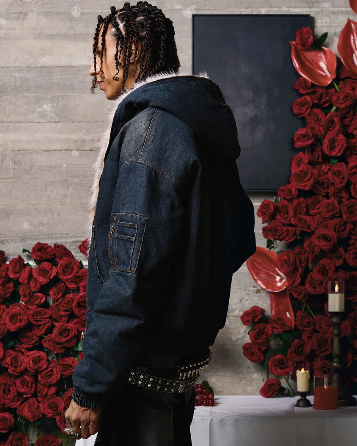 Young person in dark denim jacket with fur-trimmed hood, surrounded by red roses and candles, showcasing the Distressed Washed Faux Fur Winter Jacket's urban, warm design.