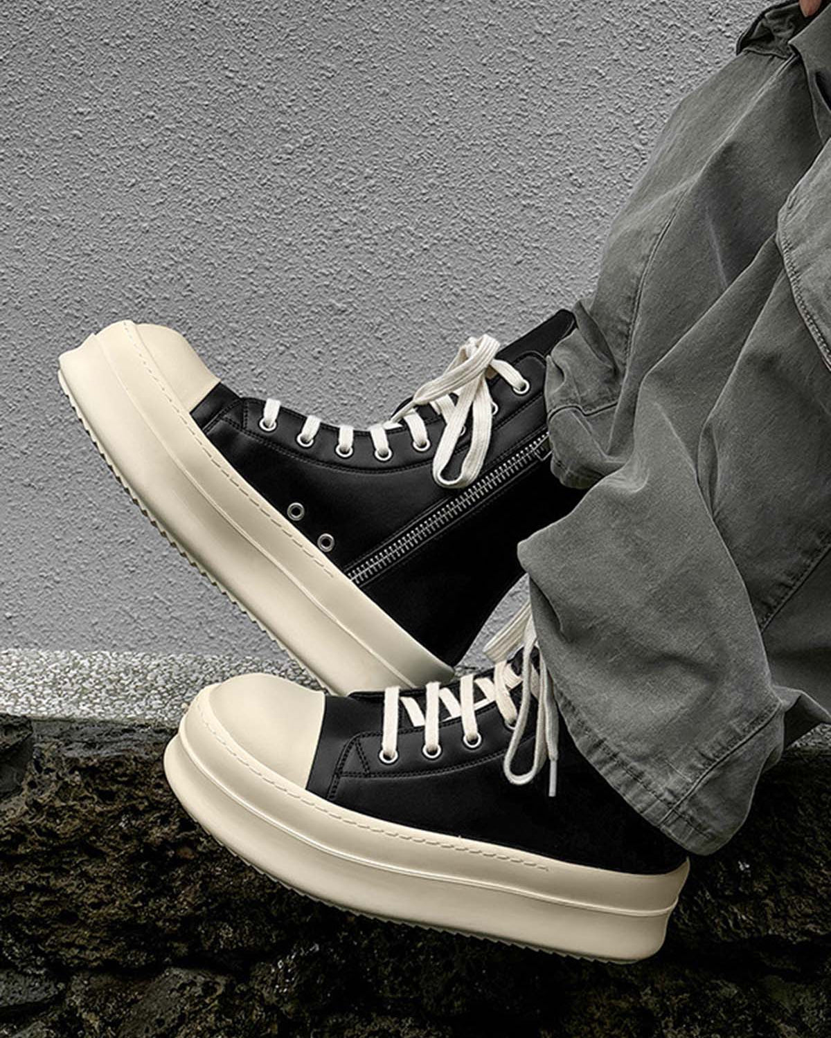 High-Top Platform Streetwear Sneakers with cream platform soles, white laces, and side zippers, worn with olive-green pants against a textured wall.