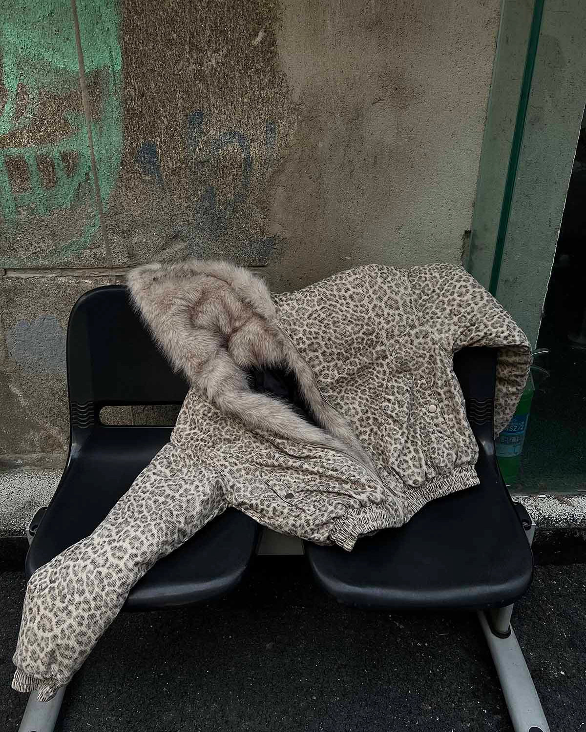 Leopard Faux Fur Hooded Jacket draped on black seats, showcasing its bold print and cozy faux-fur lining, ideal for standout winter streetwear.