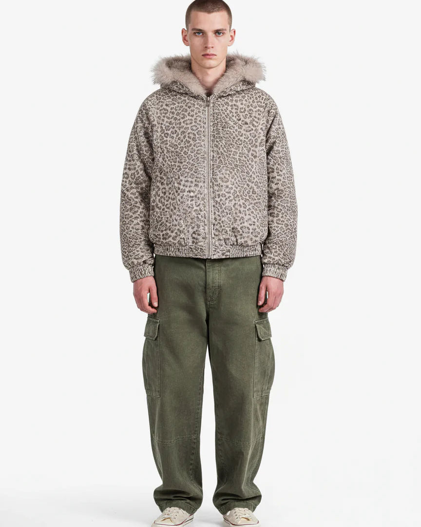 Young man wearing a Leopard Faux Fur Hooded Jacket with taupe-gray leopard print, paired with olive cargo pants and white sneakers, facing the camera in a relaxed pose.