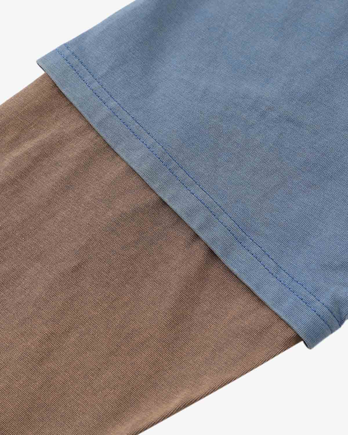 Close-up of Retro Graphic Layered Streetwear T-Shirt, showcasing sky-blue and brownish-tan layered knit fabric with double-stitched hem for a vintage streetwear look.