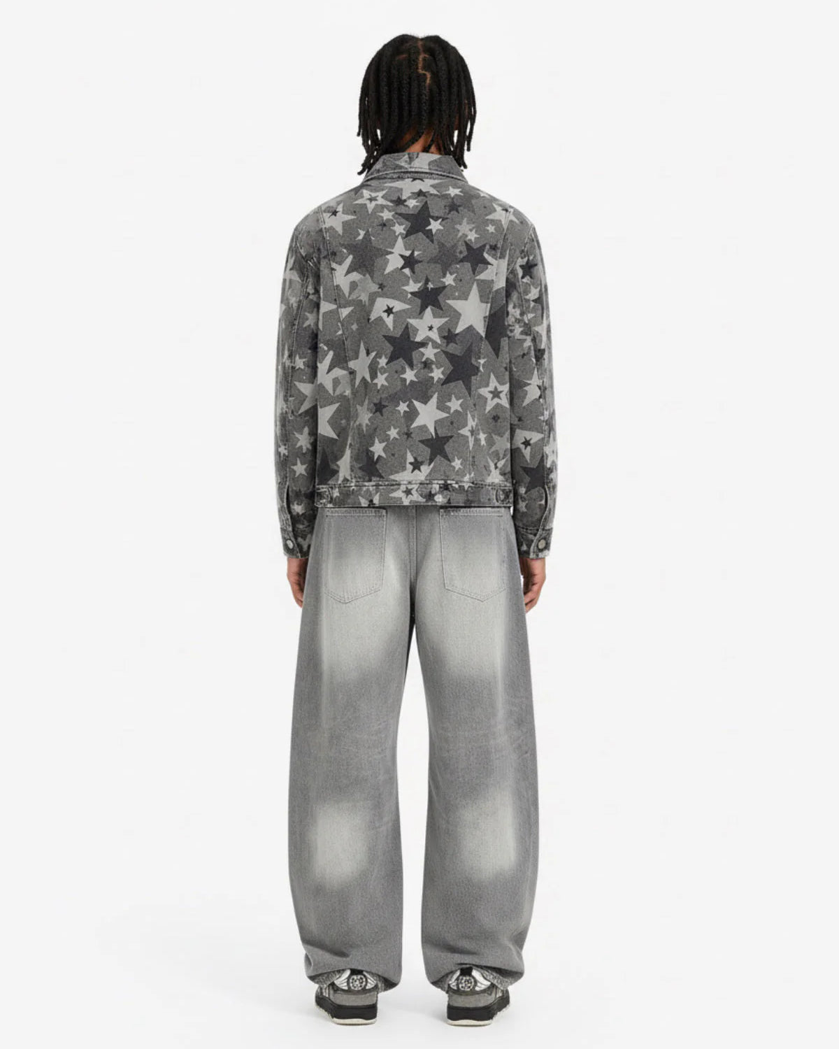 Model in Retro Washed Grey Baggy Jeans with wide-leg silhouette, faded effect, and whiskering, paired with a grey star-printed denim jacket and black-and-white sneakers.