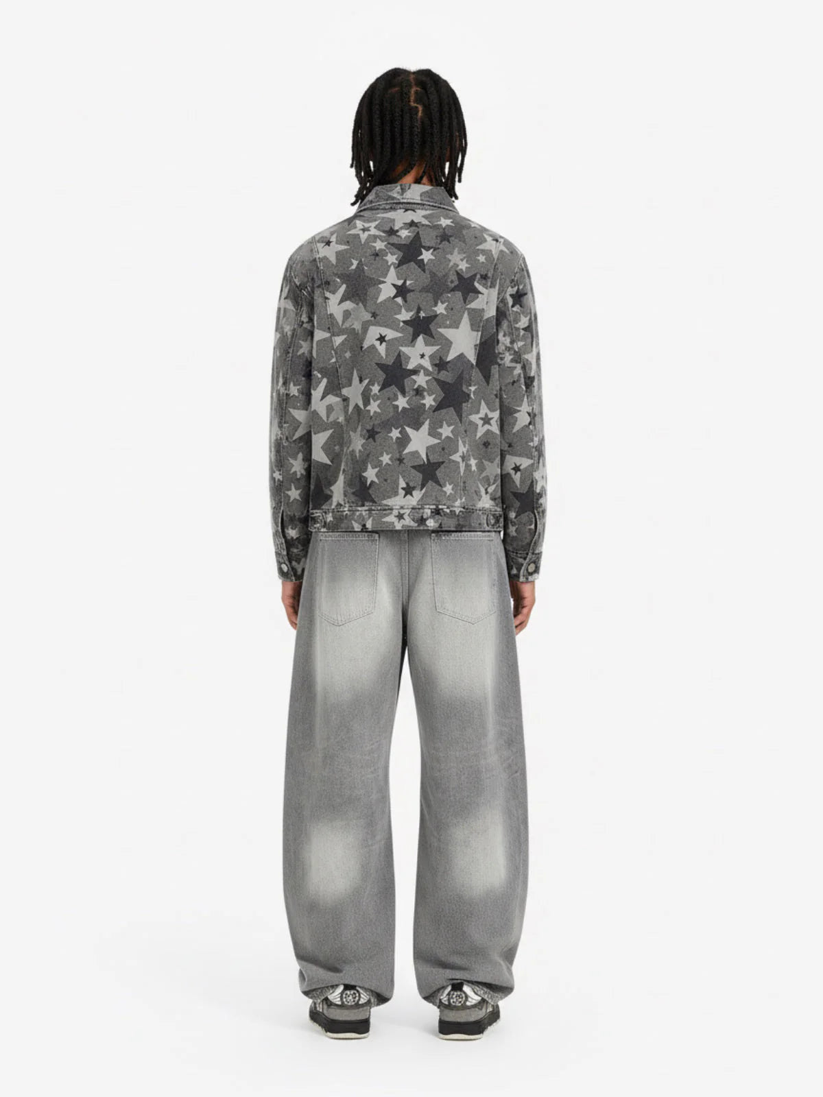 Model in Retro Washed Grey Baggy Jeans with wide-leg silhouette, faded effect, and whiskering, paired with a grey star-printed denim jacket and black-and-white sneakers.