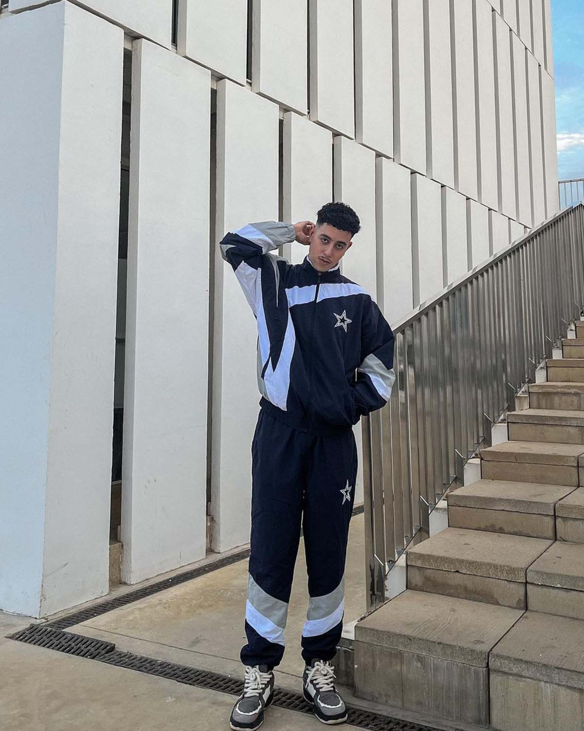 Young man in navy tracksuit wearing Vintage Chunky Graphic Skate Shoes with bold graphics and thick rope laces, embodying 90s skate style.