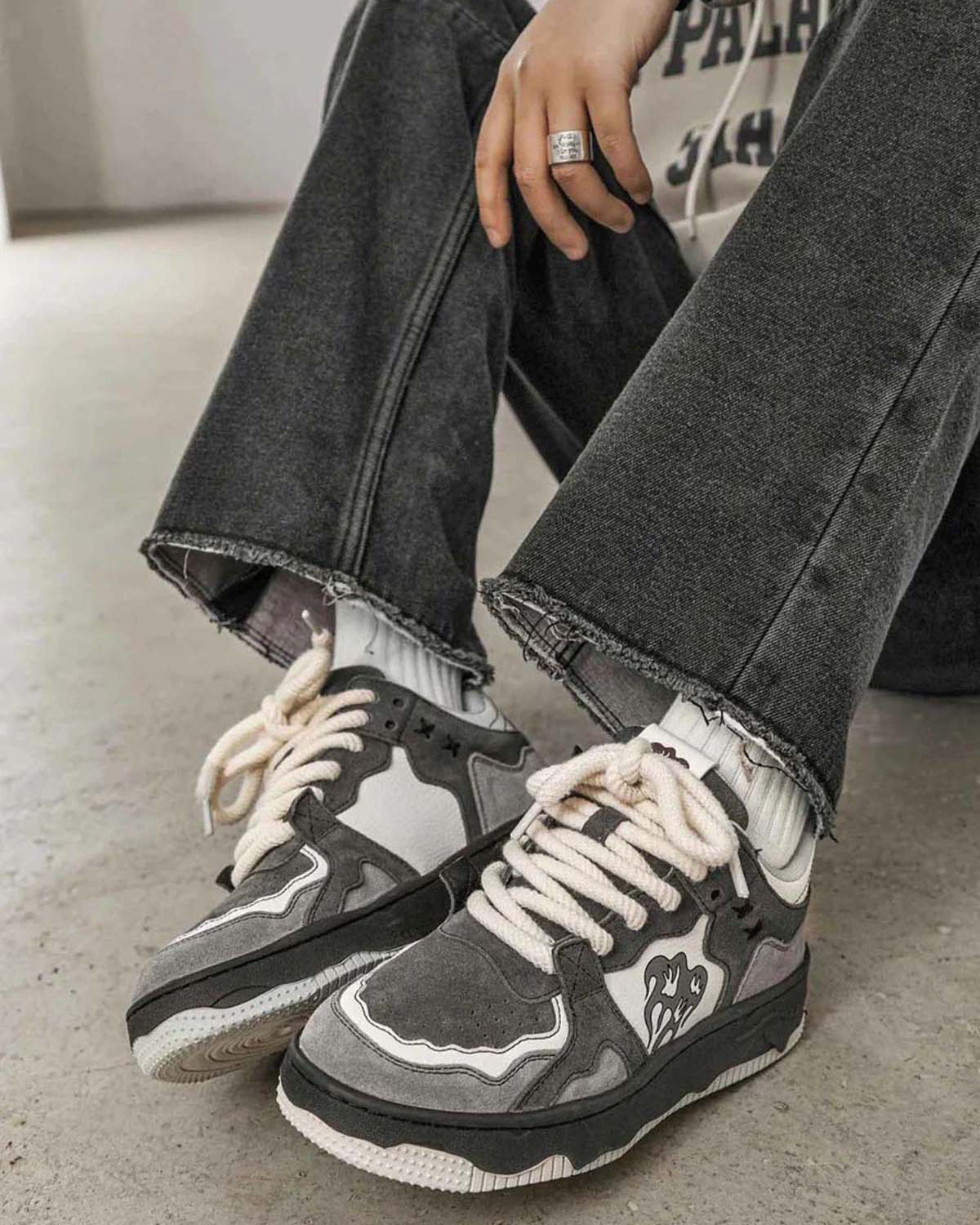 Person wearing Vintage Chunky Graphic Skate Shoes with thick rope laces and ribbed socks, highlighting the retro skate aesthetic with a chunky silhouette on a concrete floor.
