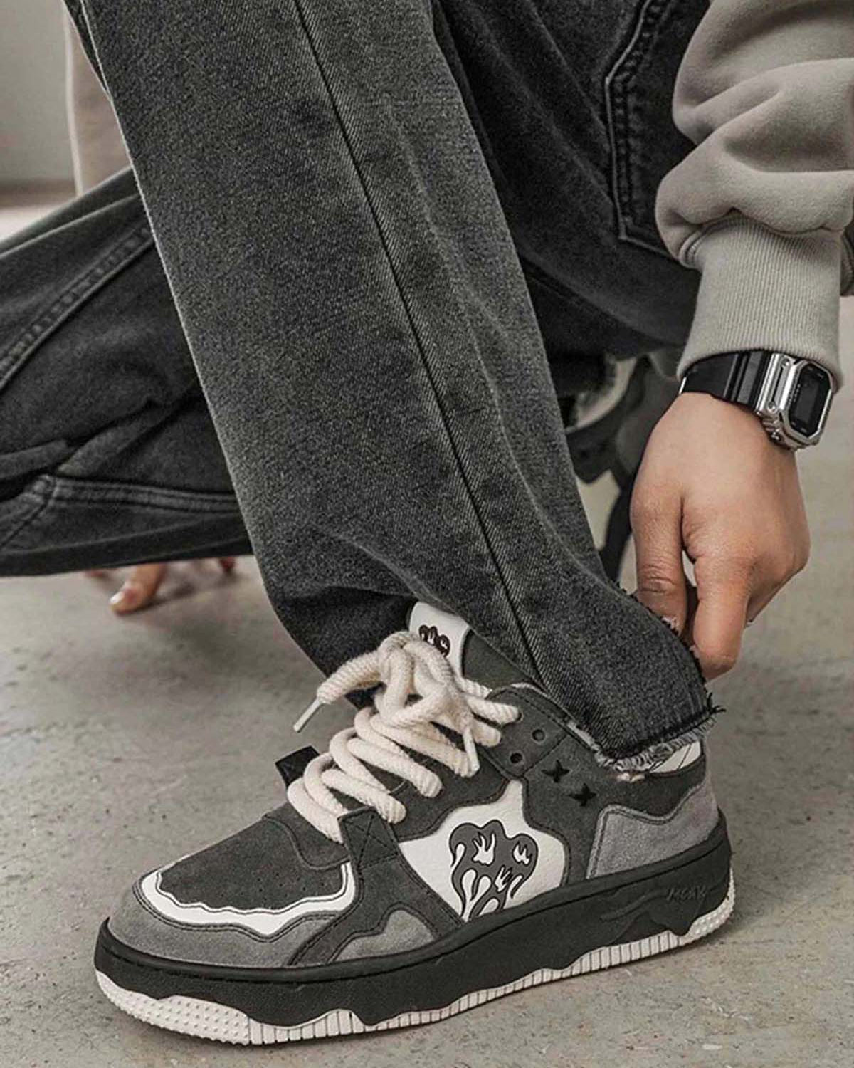 Close-up of Vintage Chunky Graphic Skate Shoes on a person kneeling, showcasing gray and black design, flame/heart graphic, and thick rope laces.