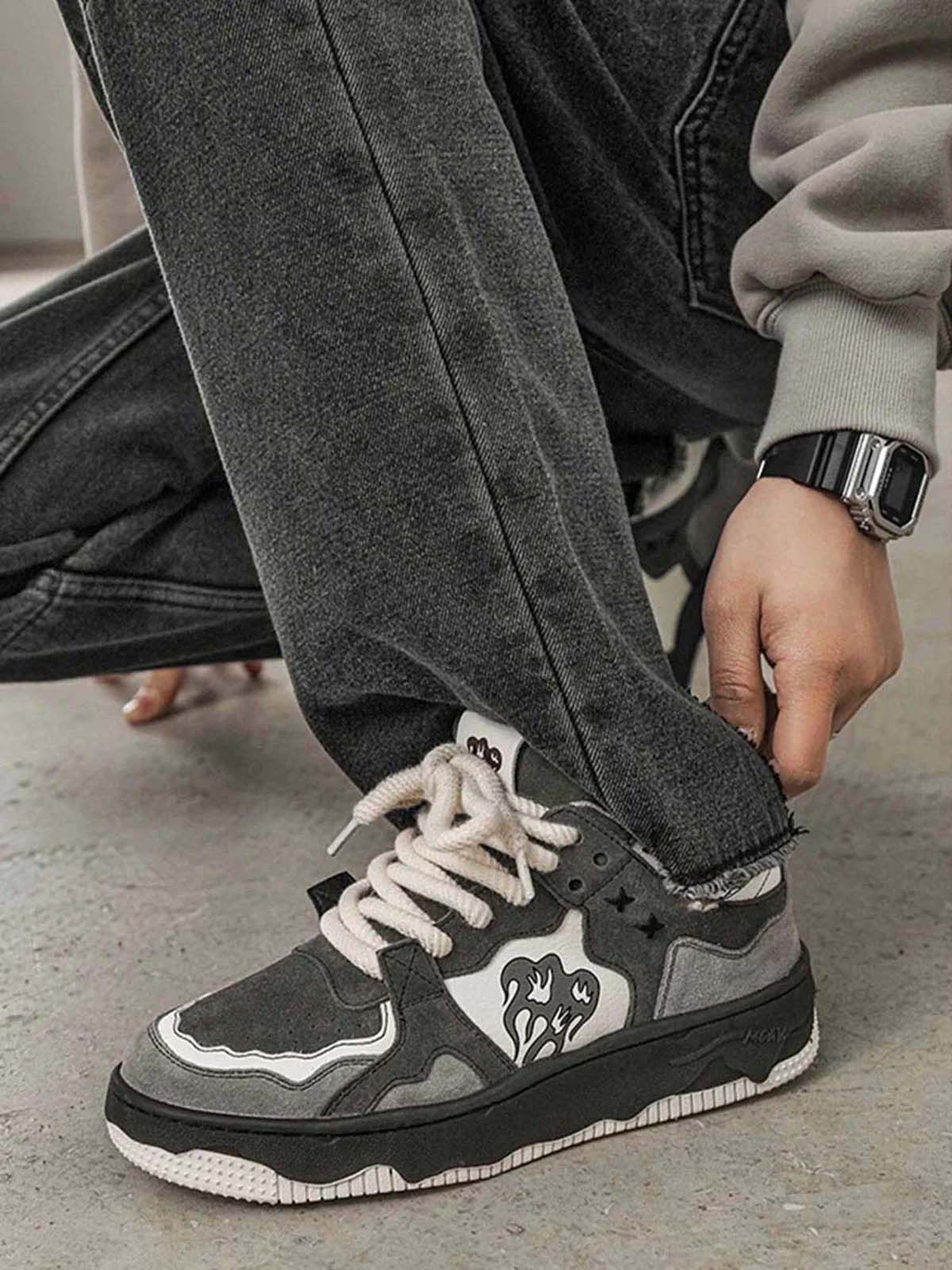 Close-up of Vintage Chunky Graphic Skate Shoes on a person kneeling, showcasing gray and black design, flame/heart graphic, and thick rope laces.