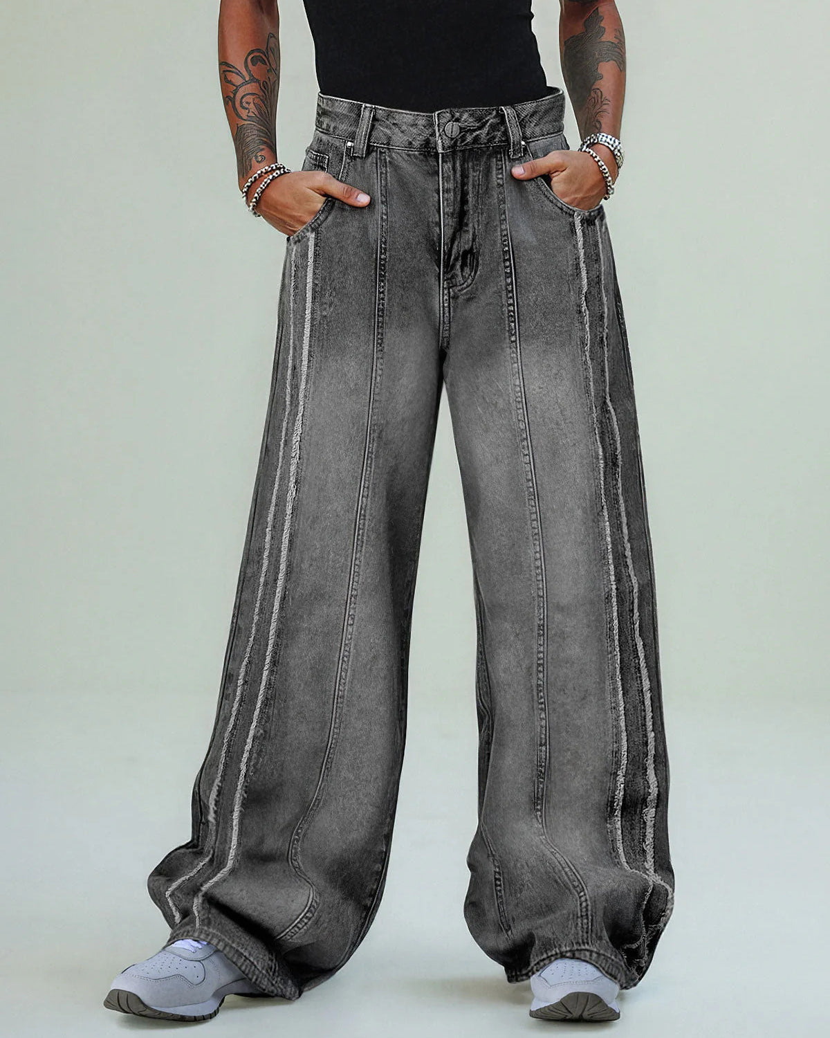 Model wearing Washed Distressed Raw-Edge Baggy Jeans with exposed seams, oversized fit, and pooling hems over light-gray sneakers. Hands in pockets, showcasing streetwear style.