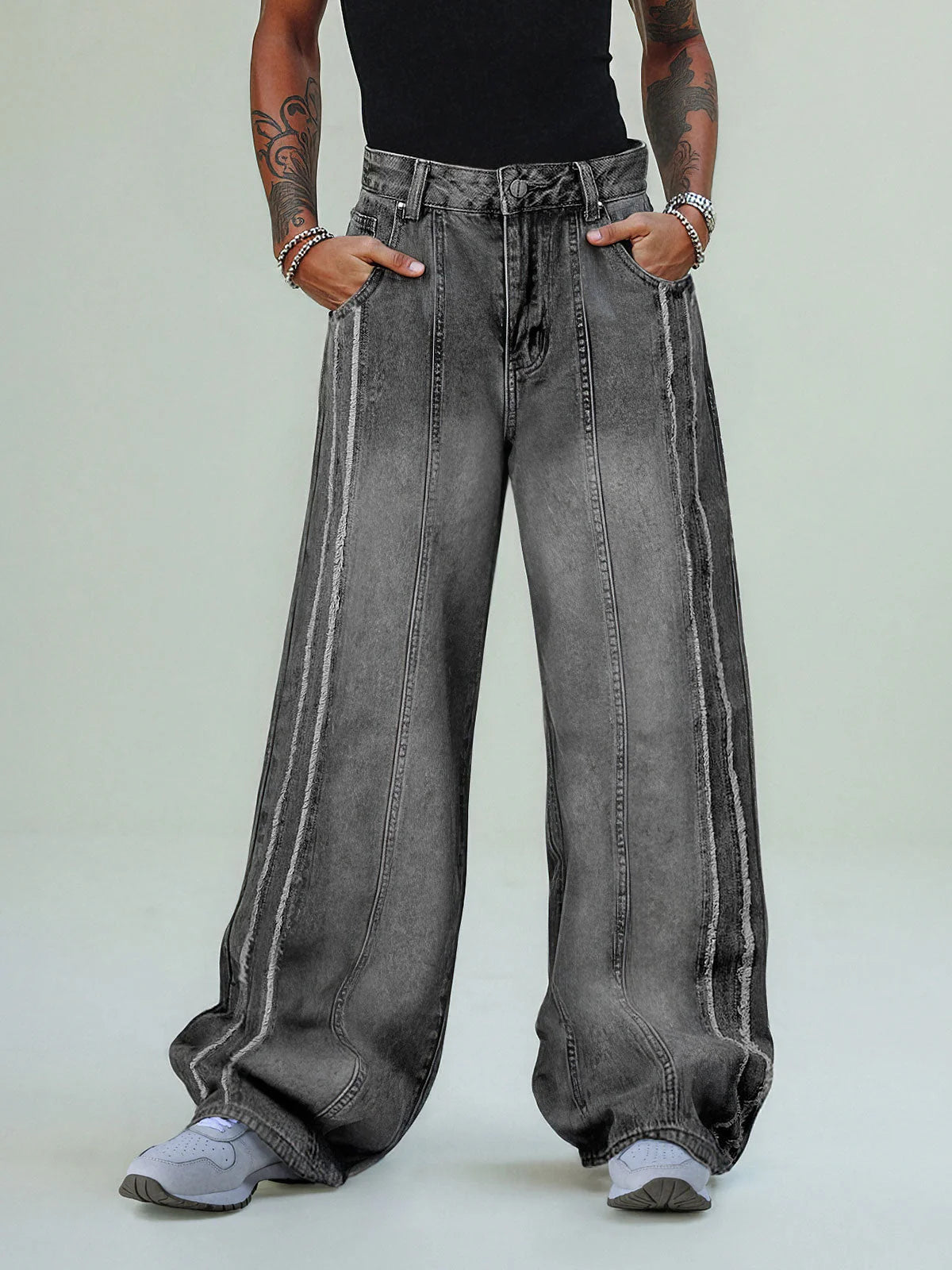 Model wearing Washed Distressed Raw-Edge Baggy Jeans with exposed seams, oversized fit, and pooling hems over light-gray sneakers. Hands in pockets, showcasing streetwear style.