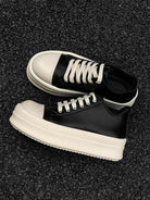 Chunky Low-Top Streetwear Sneakers with black leather uppers, white rubber toe caps, thick platform soles, and white laces, ideal for bold, modern street style.