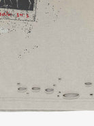 Distressed Grunge Layered T-Shirt close-up showing a speckled graphic, distressed holes, and hem, embodying vintage street style with a worn-in look.