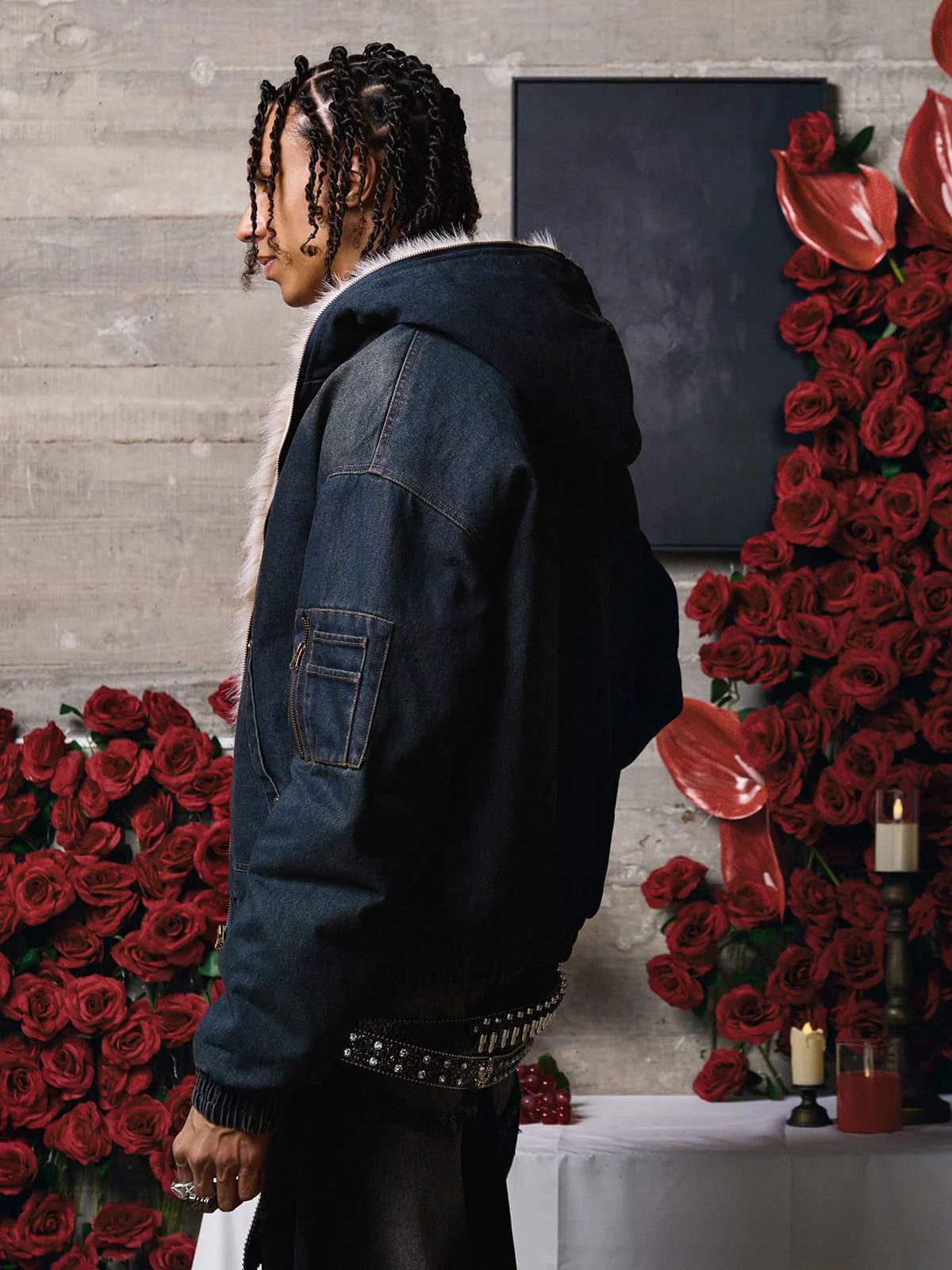 Young person in dark denim jacket with fur-trimmed hood, surrounded by red roses and candles, showcasing the Distressed Washed Faux Fur Winter Jacket's urban, warm design.