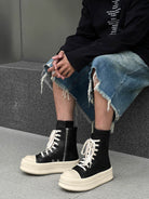 High-Top Platform Streetwear Sneakers with chunky off-white soles, black uppers, white laces, and side zipper, worn with distressed denim and black top.