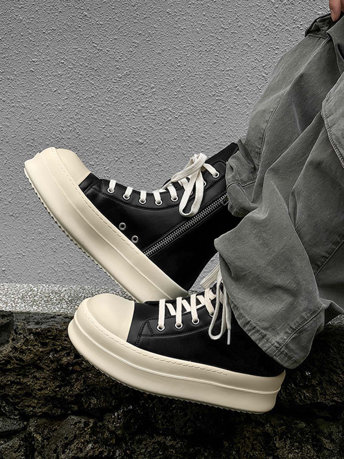 High-Top Platform Streetwear Sneakers with cream platform soles, white laces, and side zippers, worn with olive-green pants against a textured wall.