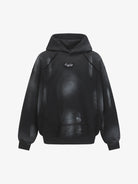 Ink Dyed Raw-Edge Streetwear Hoodie with a black oversized fit, dropped shoulders, kangaroo-style pouch, and a faded gray/white pattern, featuring a small chest emblem.