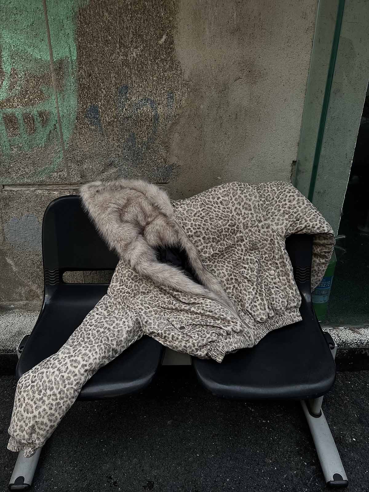 Leopard Faux Fur Hooded Jacket draped on black seats, showcasing its bold print and cozy faux-fur lining, ideal for standout winter streetwear.