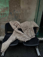 Leopard Faux Fur Hooded Jacket draped on black seats, showcasing its bold print and cozy faux-fur lining, ideal for standout winter streetwear.