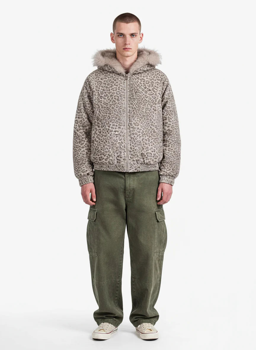 Young man wearing a Leopard Faux Fur Hooded Jacket with taupe-gray leopard print, paired with olive cargo pants and white sneakers, facing the camera in a relaxed pose.