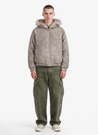 Young man wearing a Leopard Faux Fur Hooded Jacket with taupe-gray leopard print, paired with olive cargo pants and white sneakers, facing the camera in a relaxed pose.
