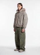 Model wearing Leopard Faux Fur Hooded Jacket with fluffy trim, paired with olive cargo pants and beige-grey sneakers, showcasing a stylish winter streetwear look.