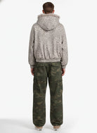 Person wearing Leopard Faux Fur Hooded Jacket with fur-trimmed hood, paired with camouflage cargo pants and low-top sneakers, showcasing a stylish winter streetwear look.