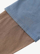 Close-up of Retro Graphic Layered Streetwear T-Shirt, showcasing sky-blue and brownish-tan layered knit fabric with double-stitched hem for a vintage streetwear look.