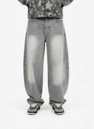 Retro Washed Grey Baggy Jeans with a wide curved-leg silhouette, faded effect on thighs and knees, styled with black-and-white sneakers for a vintage streetwear look.