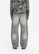 Back view of person wearing Retro Washed Grey Baggy Jeans, showcasing their wide, curved-leg silhouette and faded effect, paired with casual sneakers.