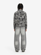 Model in Retro Washed Grey Baggy Jeans with wide-leg silhouette, faded effect, and whiskering, paired with a grey star-printed denim jacket and black-and-white sneakers.