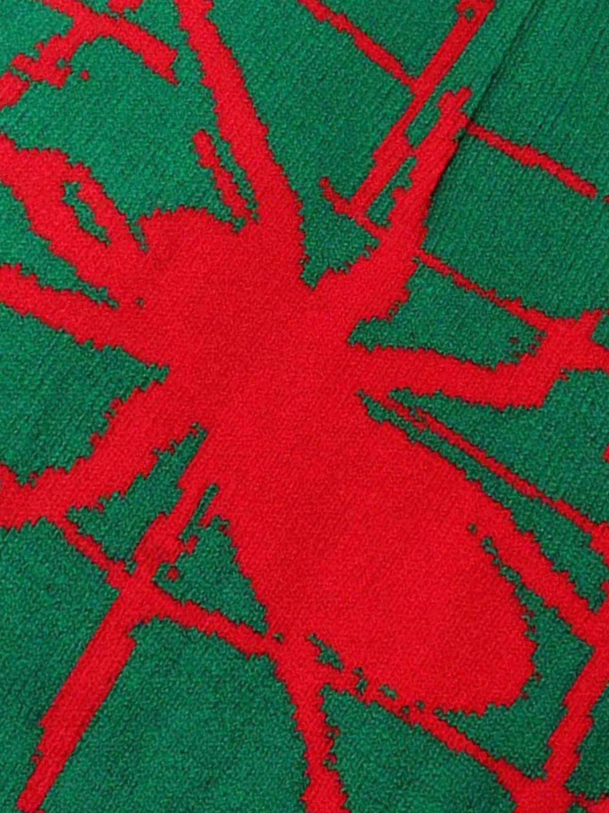 Close-up of the Spider Web Graphic Knit Hat featuring a green knit textile with a red, stylized spider silhouette, emphasizing its bold streetwear aesthetic.