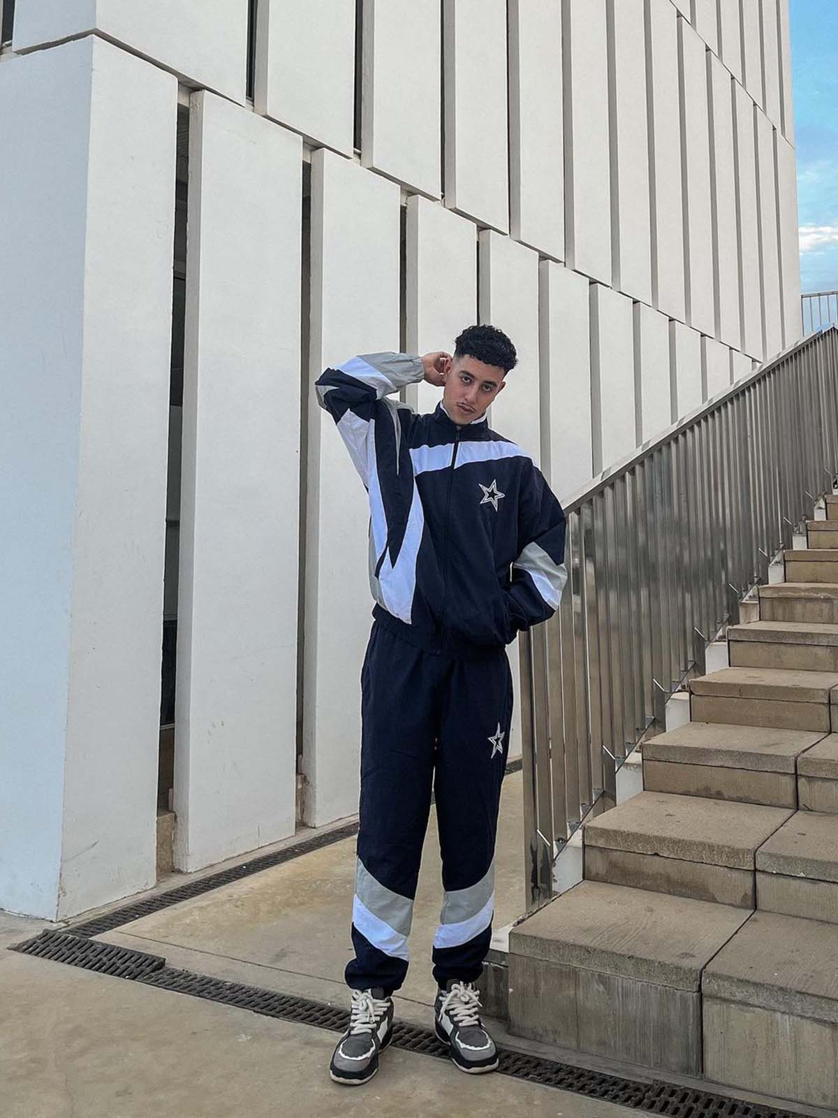 Young man in navy tracksuit wearing Vintage Chunky Graphic Skate Shoes with bold graphics and thick rope laces, embodying 90s skate style.