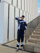 Young man in navy tracksuit wearing Vintage Chunky Graphic Skate Shoes with bold graphics and thick rope laces, embodying 90s skate style.
