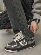 Close-up of Vintage Chunky Graphic Skate Shoes on a person kneeling, showcasing gray and black design, flame/heart graphic, and thick rope laces.