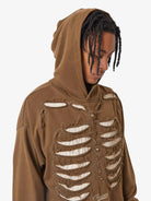 Person wearing a Washed Skeleton Graphic Streetwear Hoodie with a ribcage cut-out design, distressed finish, oversized fit, and hood over braided hair.