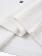 White Waffle Cross Graphic Long Sleeve T-Shirt showcasing waffle-knit texture, bold cross graphics, and a relaxed fit, embodying vintage streetwear and grunge styling.