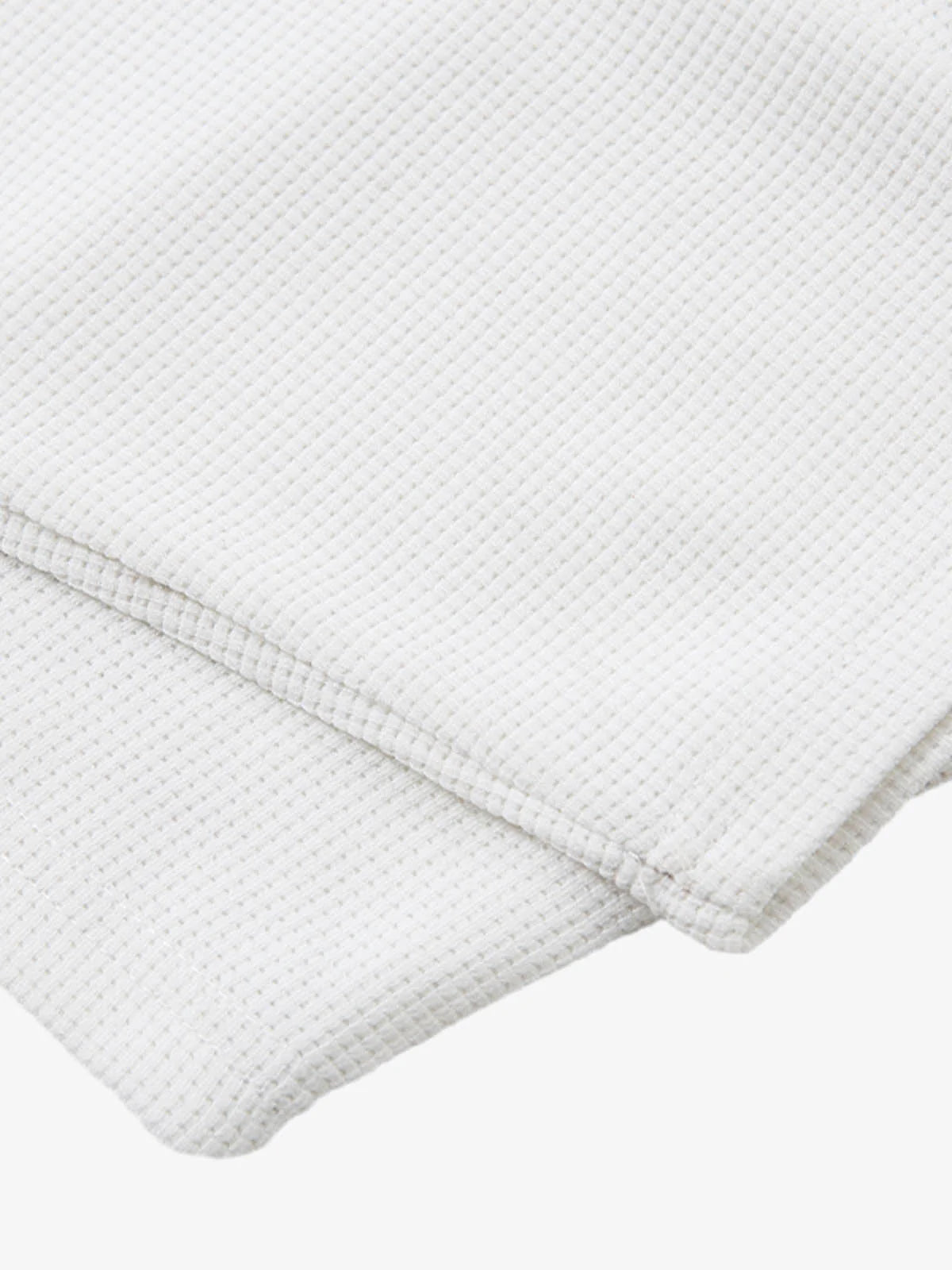 White Waffle Cross Graphic Long Sleeve T-Shirt, featuring a waffle-weave texture with bold cross graphics, neatly folded to showcase its grunge-inspired, streetwear style.