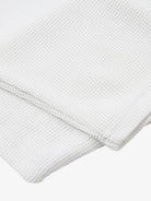 White Waffle Cross Graphic Long Sleeve T-Shirt, featuring a waffle-weave texture with bold cross graphics, neatly folded to showcase its grunge-inspired, streetwear style.